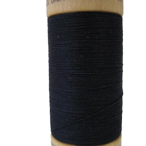 May include: A spool of black organic cotton thread with a wooden label that reads "Organic Cotton" and "Made in E.U."