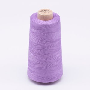 Könnte beinhalten: Eine Spule mit lilafarbenem Garn, beschriftet mit "I am organic cotton 1000 yds 30/2 wt col 4812"