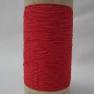 May include: A spool of red 100% organic cotton thread. The spool is labeled "100% Organic Cotton 110Y / 100M".