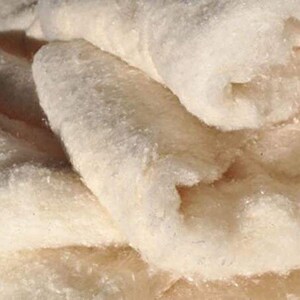 May include: Close-up of a pile of white, fluffy, natural cotton batting. The cotton is soft and textured, perfect for crafting and quilting.