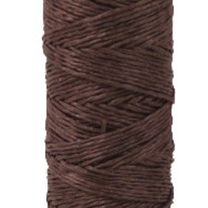 May include: A spool of brown waxed linen thread.