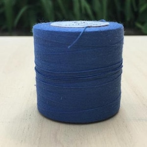 May include: A spool of blue thread wound around a cardboard tube.