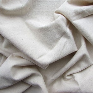 May include: A close-up of a white fabric with a textured surface. The fabric is folded and wrinkled, creating a soft and natural look.