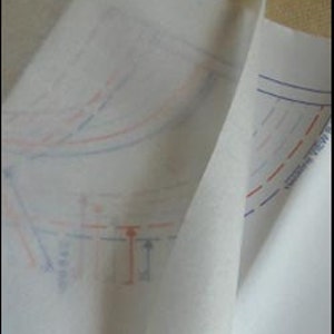 May include: Two sheets of white tissue paper with blue and red lines drawn on them. The lines are in the shape of a pattern for sewing.