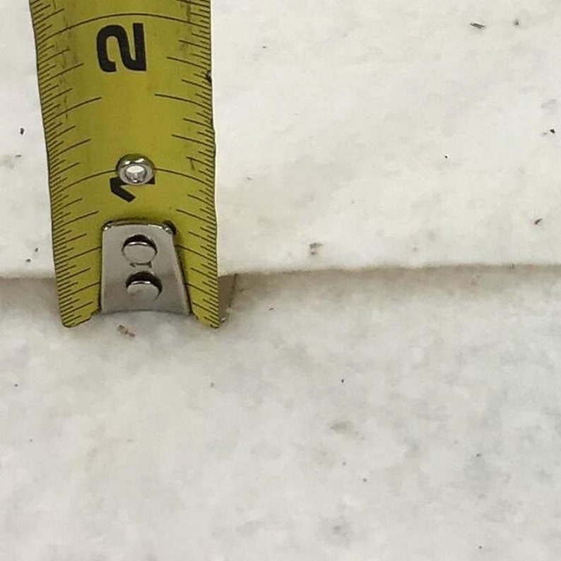 May include: A yellow measuring tape with black markings is placed on a white surface. The tape reads "1" and "2".