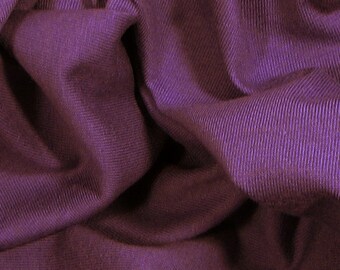 May include: Close-up of a deep purple fabric with a ribbed texture. The fabric is wrinkled and folded, creating a soft, drapey look.