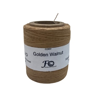 May include: A spool of Golden Walnut coloured waxed linen thread. The thread is wound around a cardboard spool with a white label that reads "Golden Walnut" and "FO Crafts & Goods".
