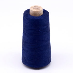 Könnte beinhalten: Eine Spule dunkelblauen Fadens mit der Aufschrift "i am organic" und "3000 yds 100% cotton col 4854" auf dem Etikett.