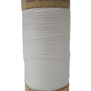 May include: A spool of white organic cotton thread with a wooden bobbin. The bobbin is labeled "100% ORGANIC COTTON" and "E.U. 110Y"