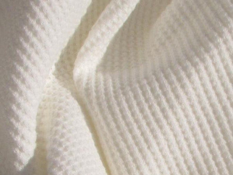 May include: White waffle weave fabric with a textured pattern. The fabric is soft and fluffy, and it has a slightly raised texture.