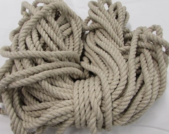May include: A large pile of natural-colored rope, likely made of cotton or hemp, is tightly wound together. The rope is thick and has a rough texture.