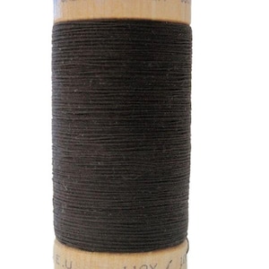May include: A spool of brown organic cotton thread with a wooden label that reads "ORGANIC COTTON 110Y / 100%"