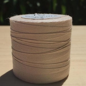 May include: A spool of beige cotton thread with a label that reads "100% Cotton Sewing Thread".