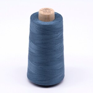 Könnte beinhalten: Eine Spule blauen Bio-Baumwollgarns auf einer Holzspule. Das Etikett lautet "I am organic cotton", "3000 yds", "30/2 wt" und "Col 4819".