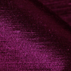May include: Close-up of a deep purple fabric with a textured, woven pattern. The fabric has a subtle sheen and a soft, luxurious feel.