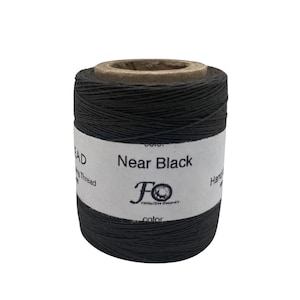 May include: A spool of dark grey waxed thread labelled "Near Black" with the "FO" logo. The thread is for hand sewing.