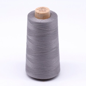 Könnte beinhalten: Eine Spule grauen Bio-Baumwollgarns mit einer Holzspule. Das Etikett lautet "I am organic cotton", "3000 yds", "30/2 wt" und "Col 4832".