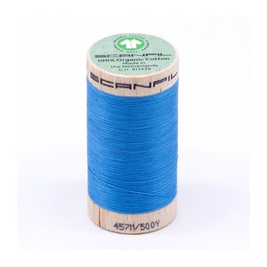 Puede incluir: Una bobina de hilo de algodón orgánico azul con una etiqueta que dice "SCANFIL 100% Algodón Orgánico Hecho en los Países Bajos C.U. 815526" y "457M/500Y".