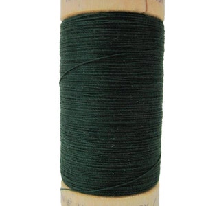 Puede incluir: Una bobina de hilo de algodón orgánico 100% verde oscuro en una bobina de madera. La bobina está etiquetada con "100% ORGANIC COTTON" y "110Y/N.E.U."