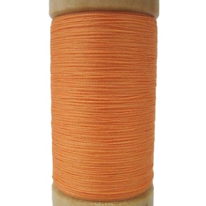 Puede incluir: Una bobina de hilo de algodón orgánico naranja de 100m.