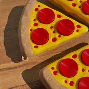 Three Pizza Slice Fidget Clicker Toys on a circular, wooden surface.
