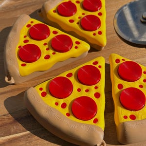 Four Pizza Slice Fidget Clicker Toys on a circular, wooden surface. Pizza cutter blade is partially visible.