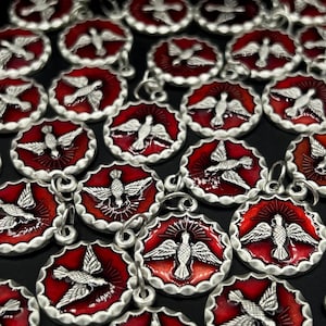 May include: A collection of round, red pendants with a silver dove design. Each pendant has a scalloped silver border and a small loop for hanging. The pendants are arranged on a black surface.