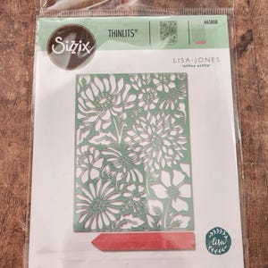 May include: Sizzix Thinlits die set featuring a floral design. The die is a light green color and has a detailed cut-out pattern of flowers and leaves. The packaging includes the Lisa Jones logo and the text "2 DIES | 2 MATRICES | 2 TROQUELES | 2 FUSTELLE".