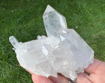May include: A cluster of clear quartz crystals with a variety of sizes and shapes. The crystals are arranged in a natural formation, with some pointing upwards and others pointing downwards. The crystals are translucent and have a slight sparkle.