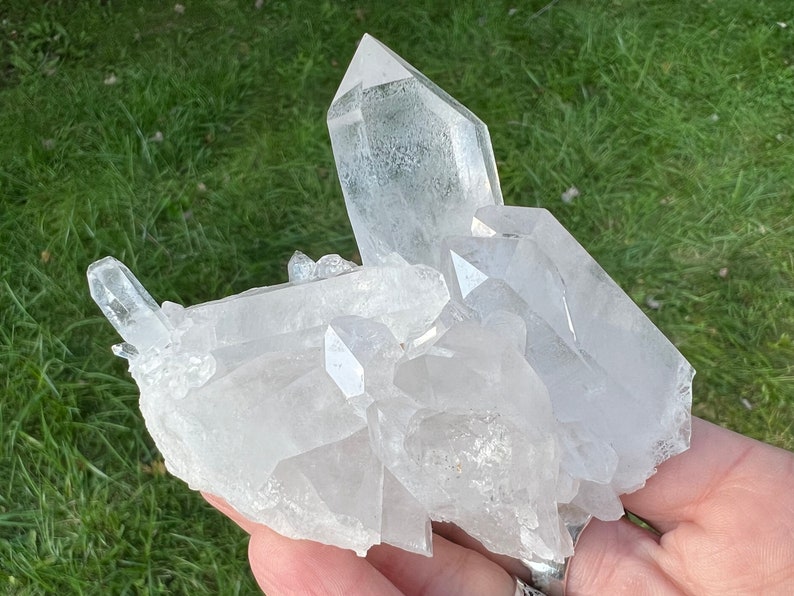 May include: A cluster of clear quartz crystals with a variety of sizes and shapes. The crystals are arranged in a natural formation, with some pointing upwards and others pointing downwards. The crystals are translucent and have a slight sparkle.