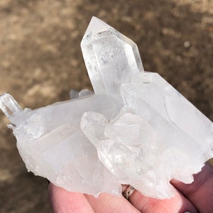 May include: A cluster of clear quartz crystals with a variety of shapes and sizes. The crystals are clustered together in a natural formation.