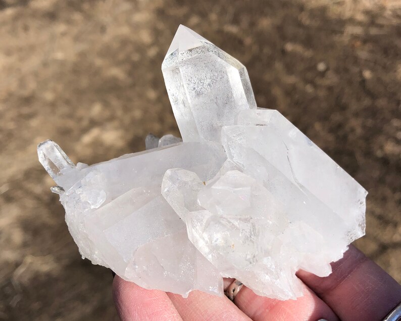 May include: A cluster of clear quartz crystals with a variety of shapes and sizes. The crystals are clustered together in a natural formation.