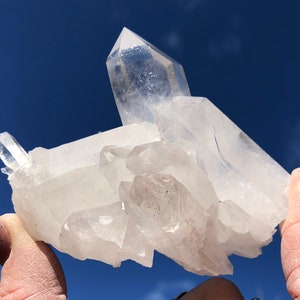 May include: A cluster of clear quartz crystals with a variety of shapes and sizes. The crystals are arranged in a way that resembles a small mountain range. The crystals are translucent and have a slight sparkle.