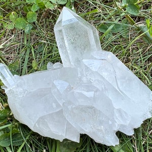 May include: A large cluster of clear quartz crystals with multiple points. The crystals are arranged in a natural formation and have a translucent appearance.