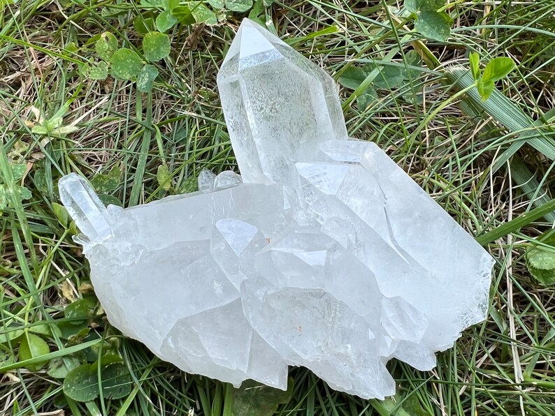 May include: A large cluster of clear quartz crystals with multiple points. The crystals are arranged in a natural formation and have a translucent appearance.