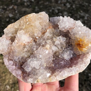 K&ouml;nnte beinhalten: Eine gro&szlig;e Amethyst-Geode mit einem Cluster aus klaren Quarzkristallen oben. Die Geode ist mit kleineren Amethystkristallen gef&uuml;llt und hat ein nat&uuml;rliches, raues &Auml;u&szlig;eres.