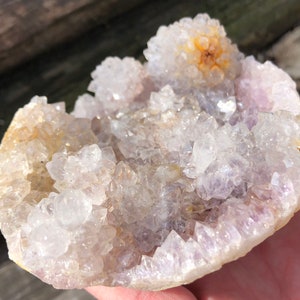 K&ouml;nnte beinhalten: Ein Cluster aus Amethystkristallen mit einem hellvioletten Farbton und einer klaren, glasartigen Oberfl&auml;che. Die Kristalle sind in einer kreisf&ouml;rmigen Formation angeordnet und bilden eine nat&uuml;rliche Geode.