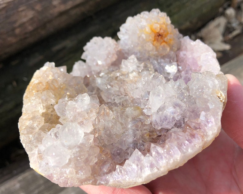 K&ouml;nnte beinhalten: Ein Cluster aus Amethystkristallen mit einem hellvioletten Farbton und einer klaren, glasartigen Oberfl&auml;che. Die Kristalle sind in einer kreisf&ouml;rmigen Formation angeordnet und bilden eine nat&uuml;rliche Geode.