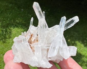 May include: A cluster of clear quartz crystals with a natural, rough texture. The crystals are arranged in a random, organic pattern, creating a unique and eye-catching display.