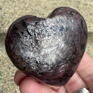 以下が含まれることがあります： 銀色と紫色のハート型の研磨された石。石は粗くて質感のある表面をしています。