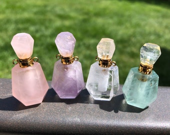 May include: Four crystal perfume bottles with gold stoppers. The bottles are in shades of pink, purple, clear, and green.