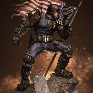 May include: A detailed figurine of a character in a dark blue uniform, black helmet with red visor, and holding a gun. The figure stands on a rocky base with an American flag in the background. The figure has gold accents on the shoulder and chest.