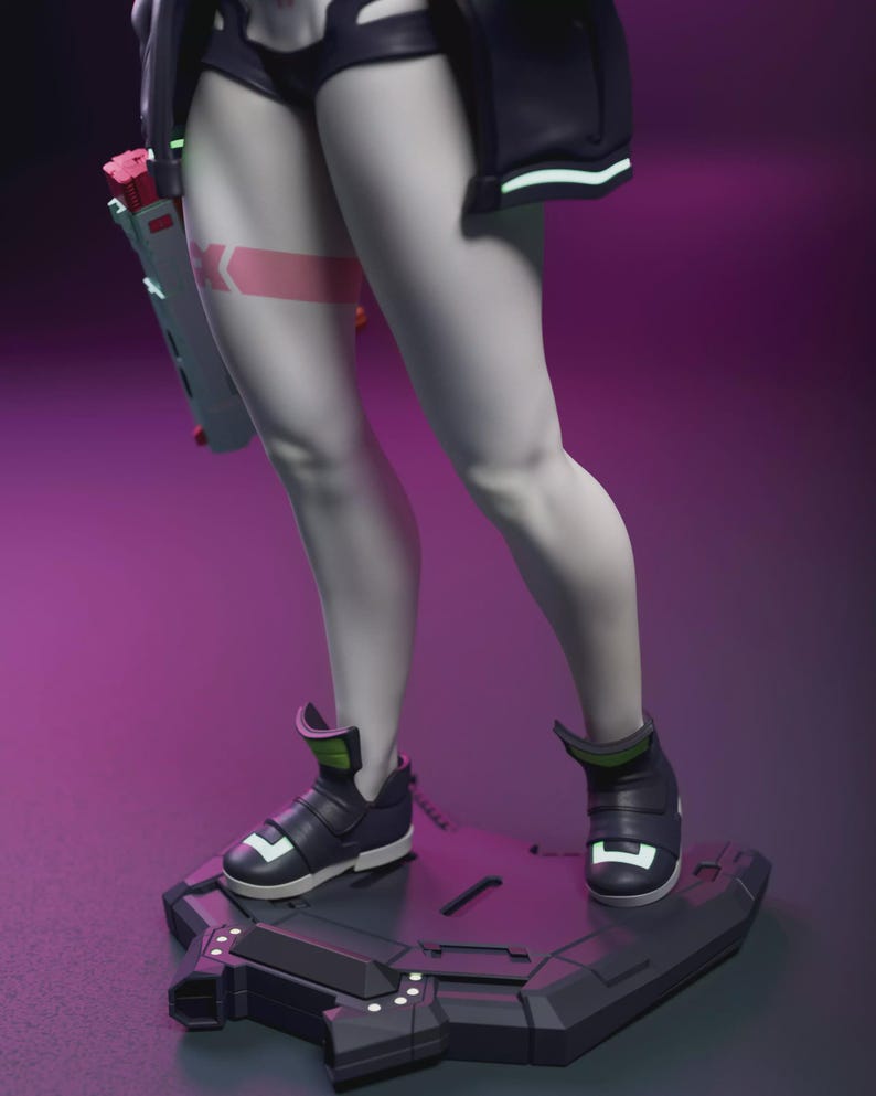 May include: A futuristic figurine featuring a character with pale skin, wearing black shorts, a jacket, and high-top sneakers. The figure stands on a geometric platform, holding a futuristic weapon. A pink band with a white "K" is on the thigh.