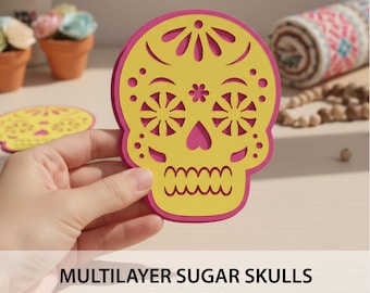May include: A layered sugar skull design in yellow and pink, held by a hand. The skull features intricate cut-out details and a decorative floral pattern. The text "MULTILAYER SUGAR SKULLS SVG BUNDLE" is displayed at the bottom.