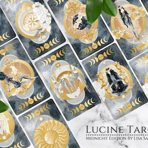 K&ouml;nnte beinhalten: Ein Tarot-Deck mit goldenen und wei&szlig;en Illustrationen auf dunkelblauem Hintergrund. Die Karten zeigen himmlische Bilder, darunter Monde, Sterne und Engel. Das Deck hei&szlig;t "Lucine Tarot: Midnight Edition by Lisa Santine".