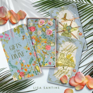 May include: A deck of oracle cards called "Gifts of the Divine" by Lisa Santine. The box features a floral design with a blue background. The cards have a light blue background with gold accents and illustrations of animals and plants.