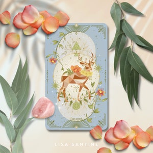 May include: The Fool tarot card features a geometric deer with antlers, surrounded by flowers and foliage. The card is blue with gold accents and the text "The Fool" at the bottom.