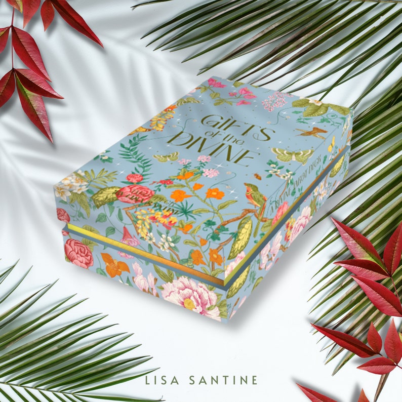 May include: A blue box with a floral pattern and gold trim. The box is titled "Gifts of the Divine" and features the author's name, Lisa Santine.