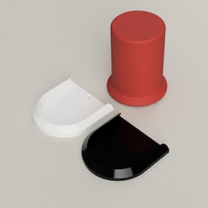 Op de afbeelding: Een rood cilindrisch object met een brede basis, naast twee gebogen, halfronde objecten. Eén is wit en de andere zwart. De objecten lijken componenten van een groter item te zijn.