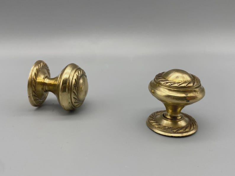 May include: A white ceramic mug with a black handle and the text "But First, Coffee" in a bold, black font. The mug is set against a neutral background, highlighting its simple design.